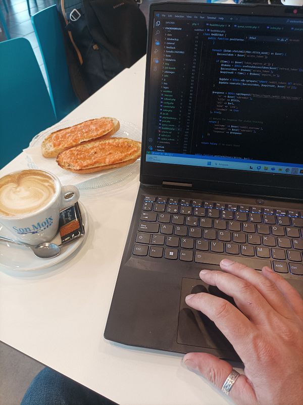 A laptop is set up on a table with a coffee and pastries, indicating a work session at a swimming club.