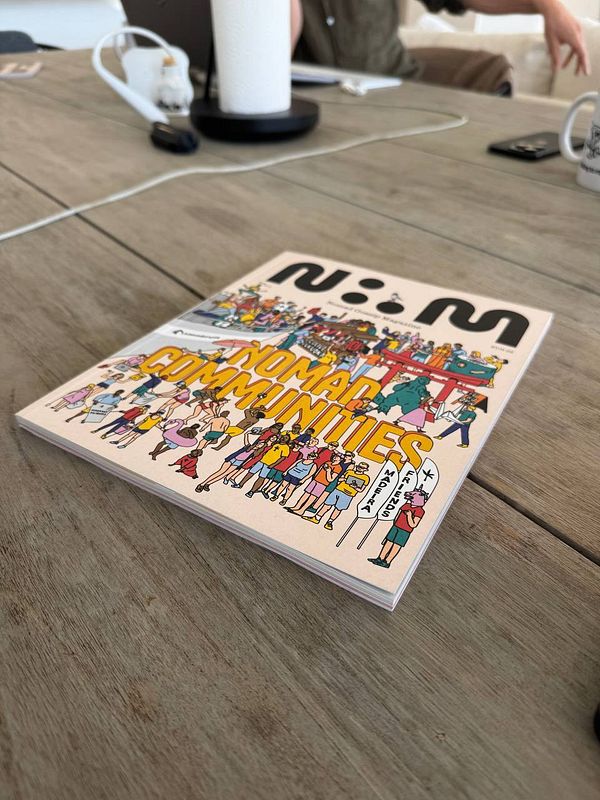A colorful magazine titled 'Nomad Communities' is prominently displayed on a wooden table.