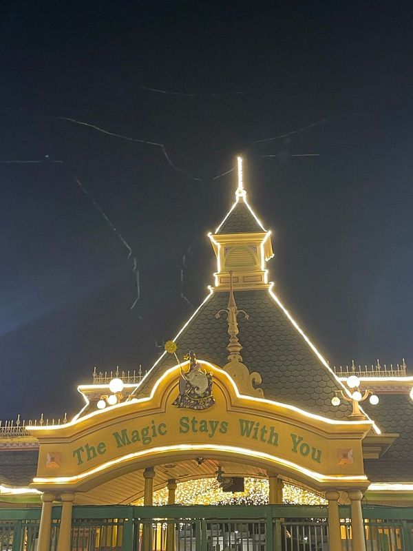 A beautifully illuminated amusement park entrance at night.