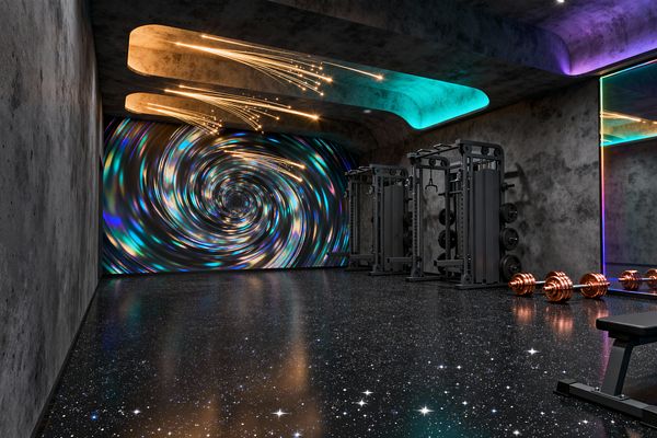 A futuristic home gym features rough concrete walls and a glossy black epoxy floor scattered with star-like specks. A swirling galaxy mural spans the far wall. Dark graphite cable machines line the right side, with copper-colored dumbbells set near a full-height mirror framed by rainbow LED lighting. Curved ceiling coves glow in cyan and purple, while fiber-optic strands create warm golden streaks. A workout bench sits in the foreground.