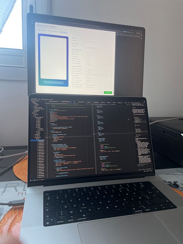Workspace with dual monitors displaying a web interface and an app interface under daylight.