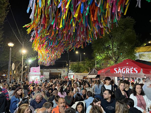 A vibrant night scene at a crowded soup festival with colorful decorations overhead.