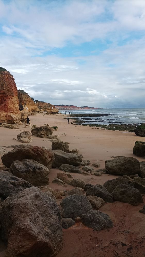 A scenic beach view at Alhos de Agus featuring rocky terrain and a cloudy sky.