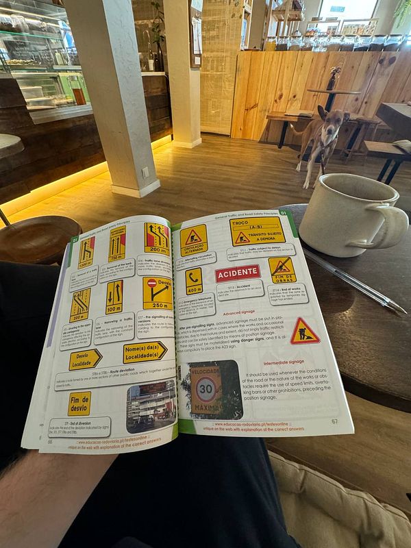 An open driving manual displaying various traffic signs in a café setting.
