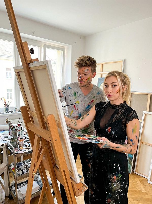 A creative scene featuring two artists engaged in painting in a bright studio.