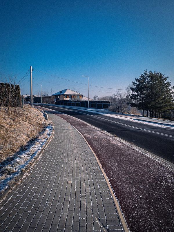 A scenic view of a winding pathway alongside a road on a clear winter morning.