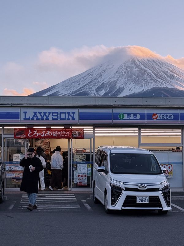 A Lawson convenience store is prominently featured in the foreground with Mt. Fuji in the background.