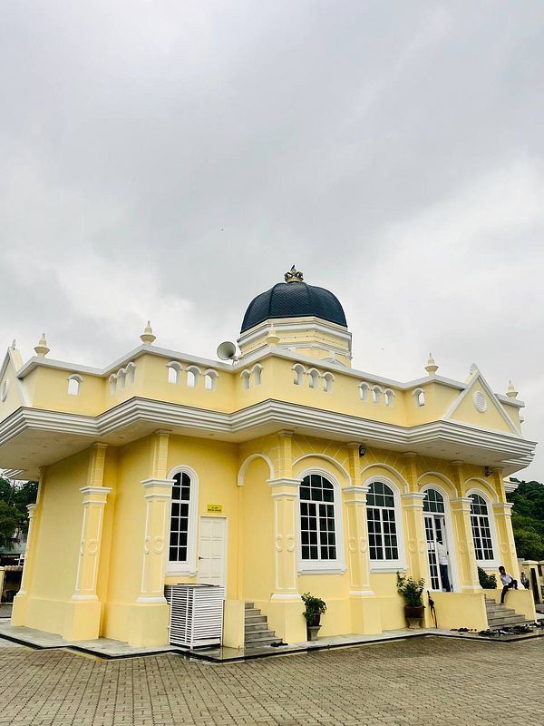 A vibrant yellow mosque with a distinctive dome and large windows.