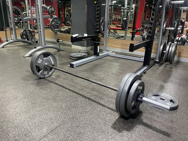 A gym setting featuring a barbell loaded with weights on a rubber floor.