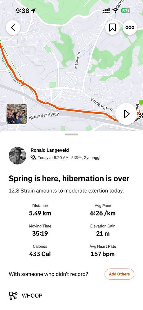 Photo of a runner's lower body in motion on an asphalt road with trees and houses in the background.