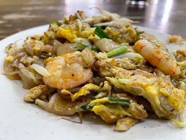 A plate of Penang char kway teow featuring shrimp, eggs, and green onions.