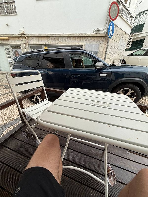 A view from a café table showing a parked car and a pedestrian area in Cascais.