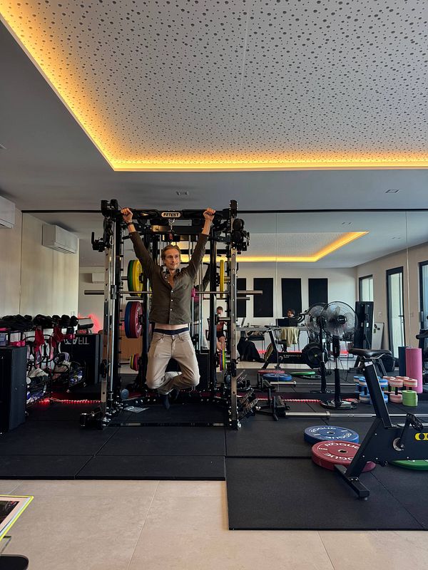 A person is performing a hanging exercise in a modern gym environment.