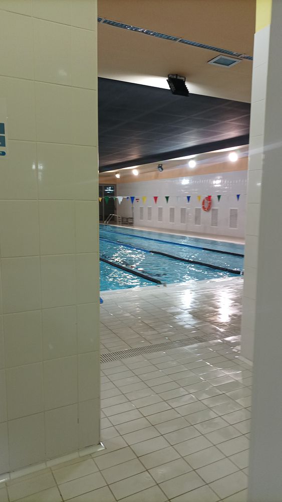 The image captures the view of an indoor swimming pool from a doorway.