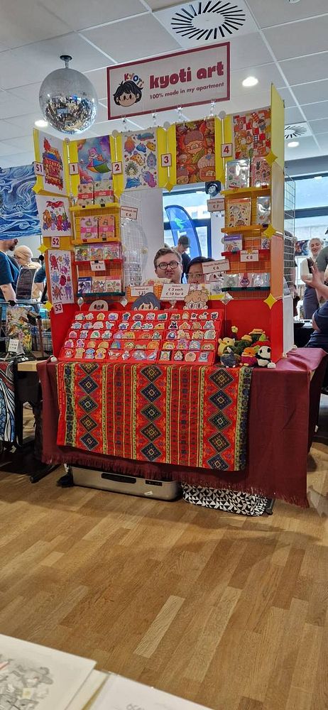 A cluttered table with board game components, including colorful cards, tiles, and tokens, arranged around a game mat.