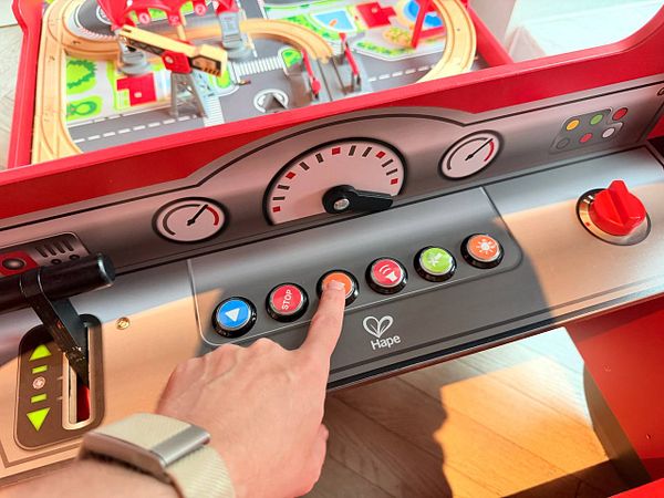 A photograph of a hotel room featuring a bed, framed pictures on the wall, and a doorway leading to another room.