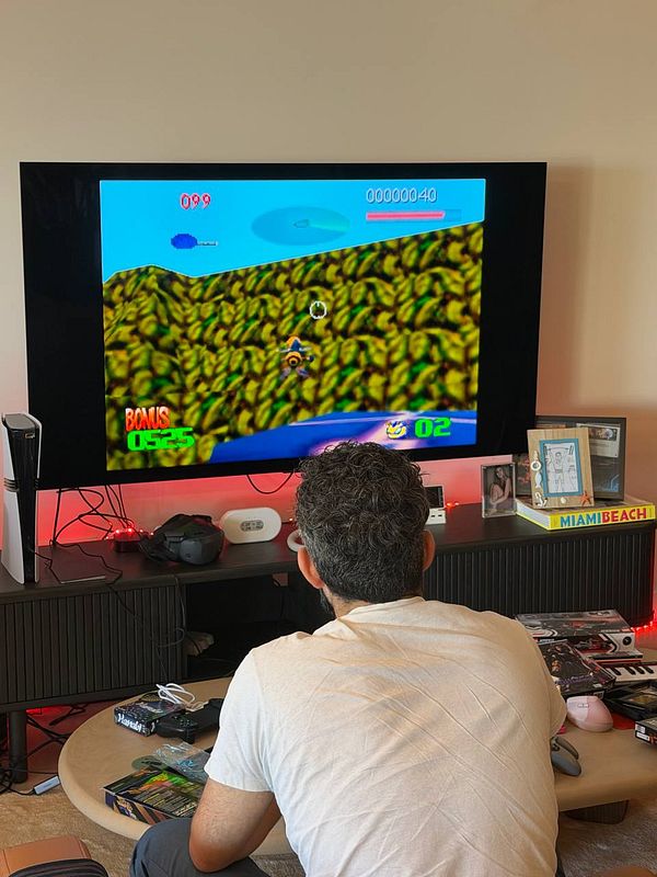 Person playing a video game on a large TV in a cozy living room setup with gaming accessories and decorative items.