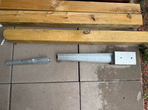 The image features metal fence post holders and wooden beams on a patio surface.