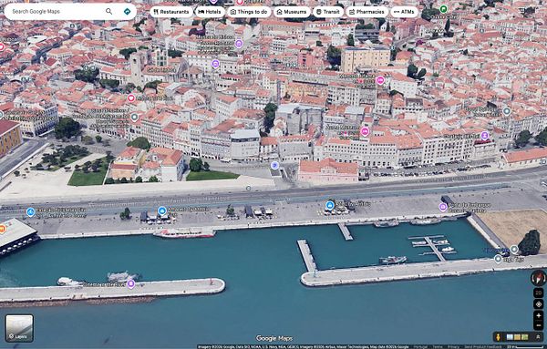 A 3D satellite view of the Alfama district in Lisbon, Portugal, showing detailed buildings, streets, and waterfront areas from Google Maps.
