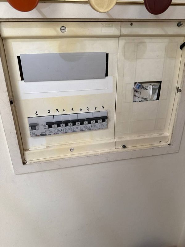 The image depicts an electric panel that is partially open, showing circuit breakers and a blank space for a main switch.