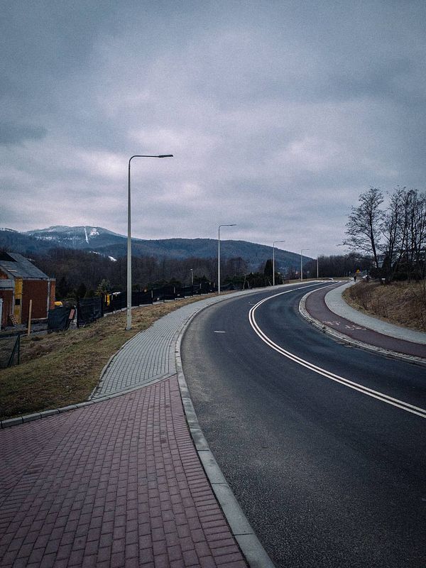 A winding road surrounded by a cloudy landscape and distant mountains.