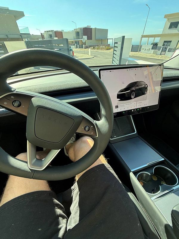 The image captures the interior of a Tesla Model Y with a focus on the steering wheel and central display.