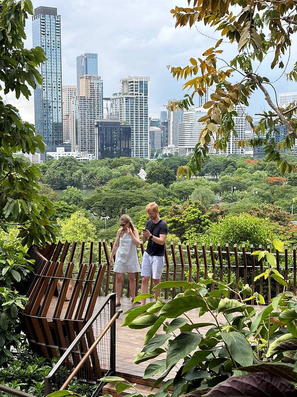 A scenic view from Go Dusit rooftop park showing outdoor seating and a vibrant cityscape under a blue sky.