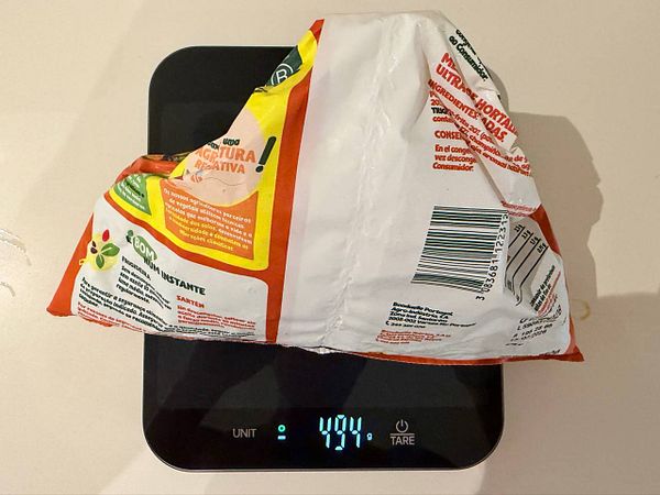 A digital kitchen scale displays a negative weight indicating food has been removed, demonstrating reverse weighing with the tare function.