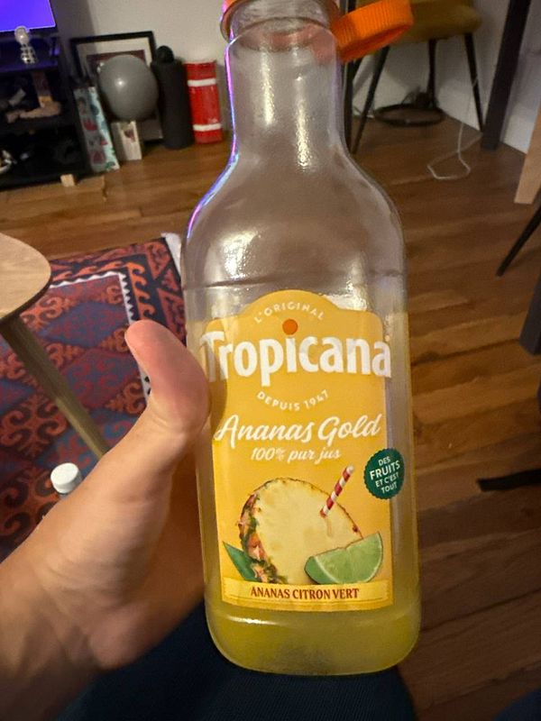 Photograph of a clear glass filled with pineapple juice on a wooden surface.