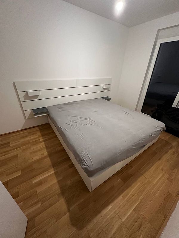 A newly assembled bed in a minimalist bedroom setting.