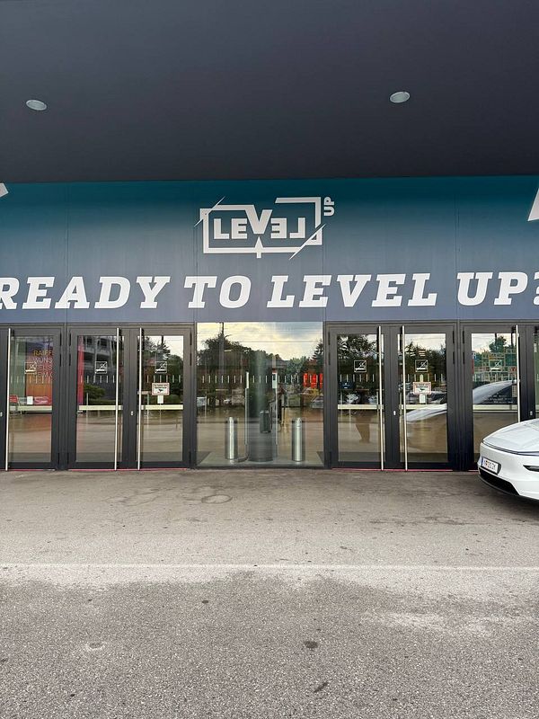 The image depicts the entrance of a venue with a large sign promoting an event.