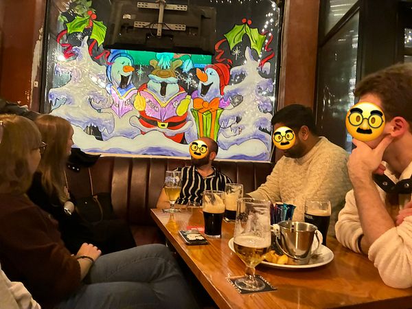 A group of friends is gathered at a pub, enjoying drinks and a festive atmosphere.