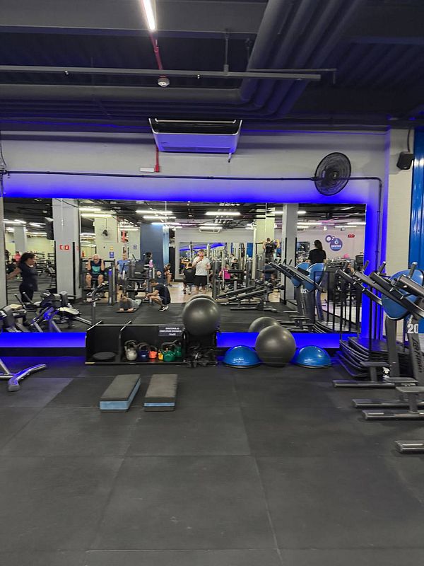 Photograph of a young athletic man standing in a gym environment with exercise equipment in the background.