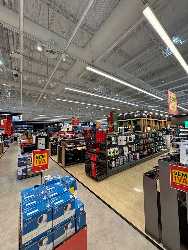 A spacious electronics store interior with various product displays and signage.