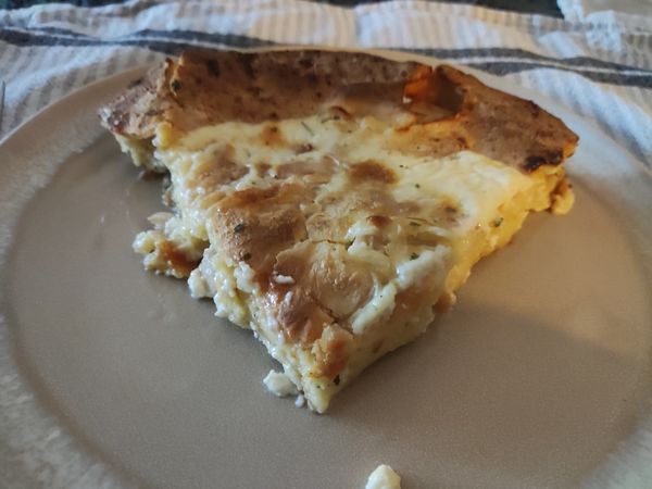 A slice of quiche is served on a plate.