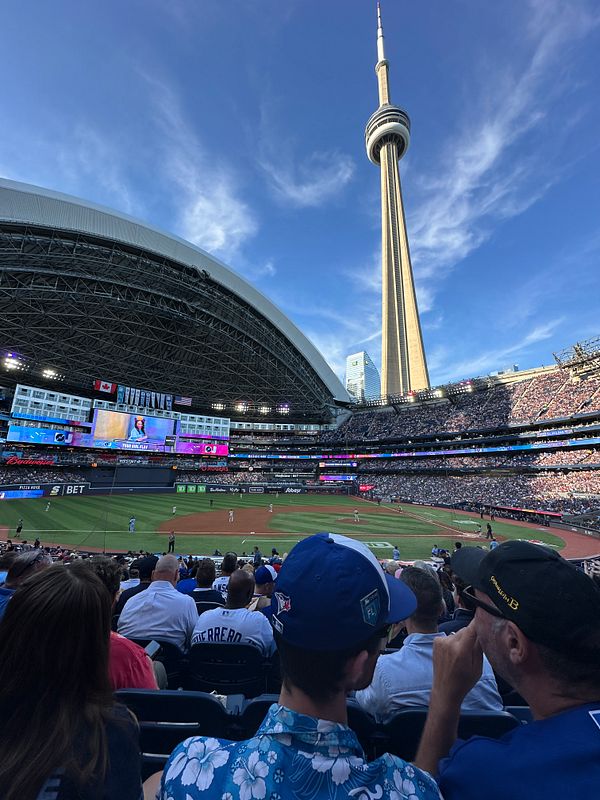 A vibrant scene from a baseball game at a stadium with the CN Tower in the background.