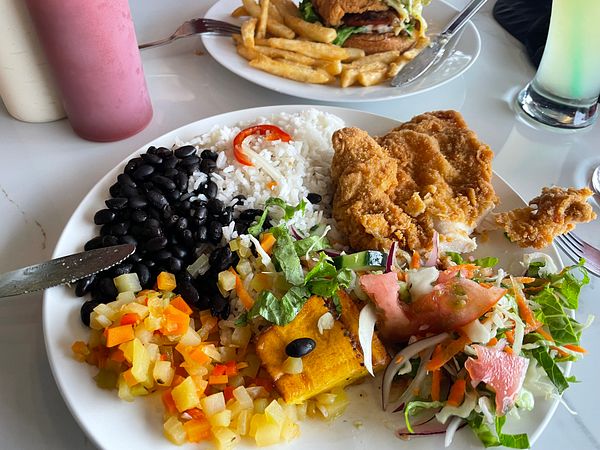 A top-down view of a delicious breakfast spread including fried eggs, sausages, avocado toast, and hash browns on a rustic wooden table.