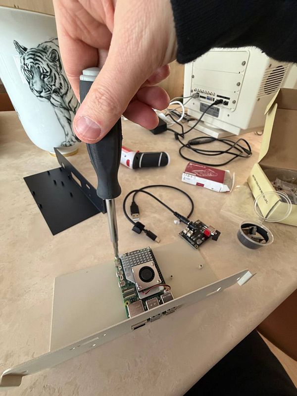 A person is assembling a Raspberry Pi inside a vintage PC monitor using a screwdriver.