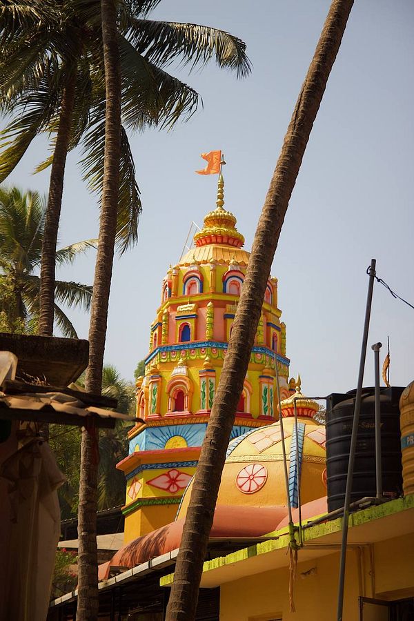 A vibrant temple structure is prominently featured among palm trees.