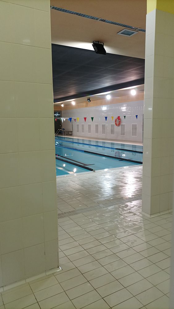 A swimmer underwater extending an arm forward, surrounded by blue water and bubbles, viewed from a side angle.