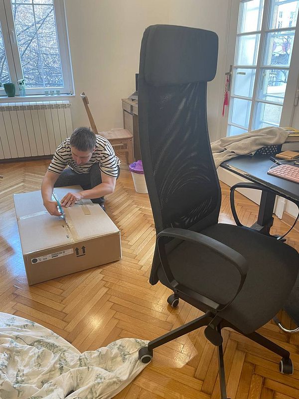 A person is assembling a MARKUS chair in a well-lit room.