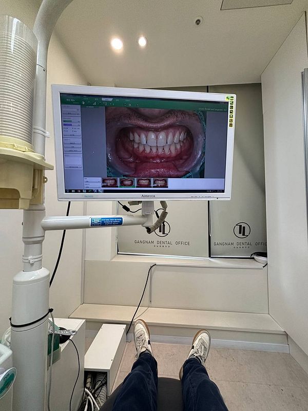 A dental office scene showing a patient's perspective with a monitor displaying an image of teeth.