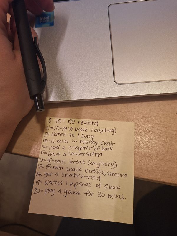 A handwritten list of rewards and breaks is displayed next to a laptop and a pen.