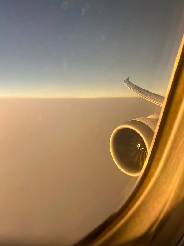 A view from an airplane window showcasing the wing and engine against a clear sky.