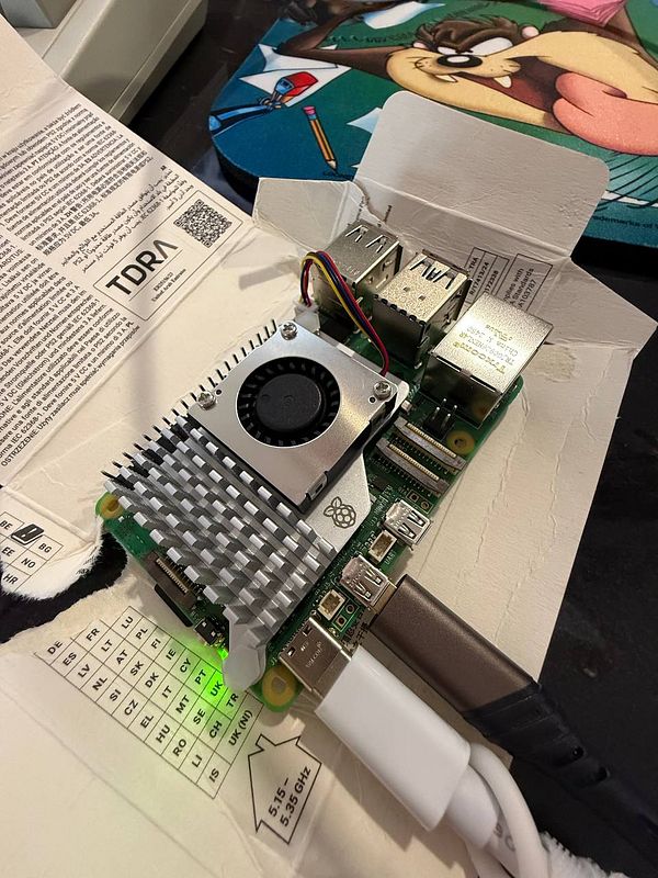 A Raspberry Pi 5 is set up on a piece of packaging with various cables connected.
