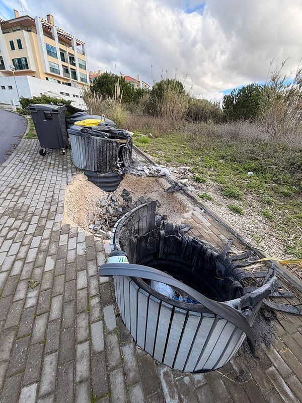 A street scene in a Portuguese neighborhood showing a road with several infrastructure issues.