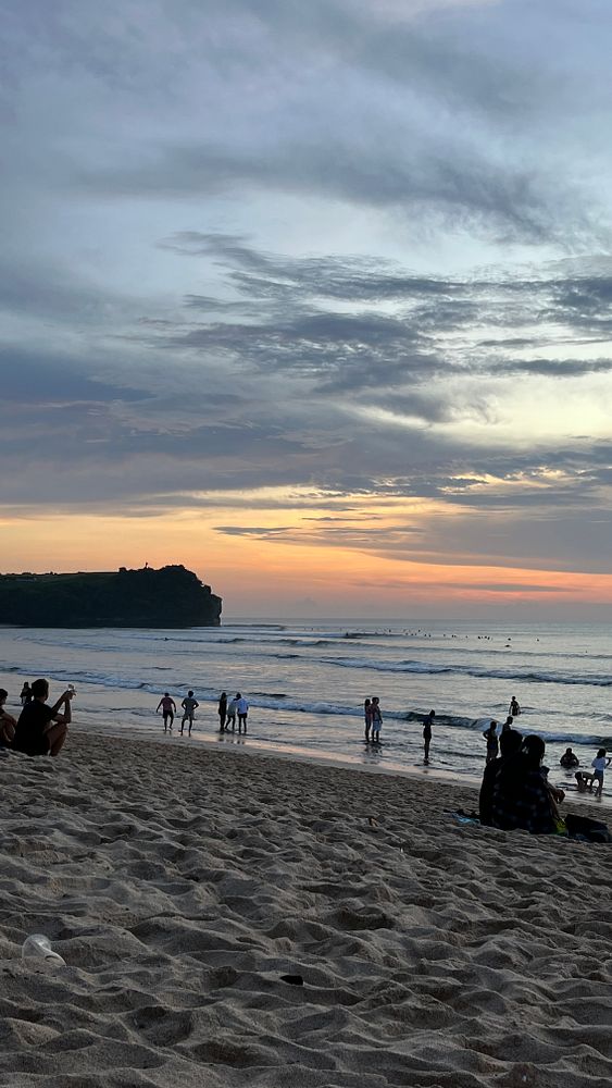 A serene beach scene at sunset with people enjoying the shoreline.