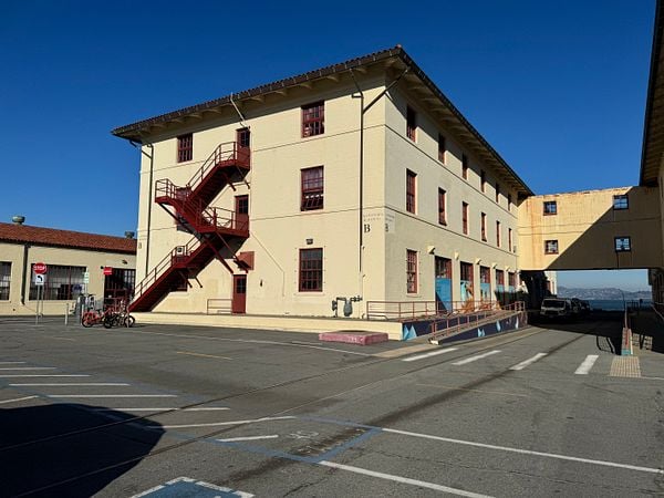 A historic building with a red staircase and parking area under a clear blue sky.