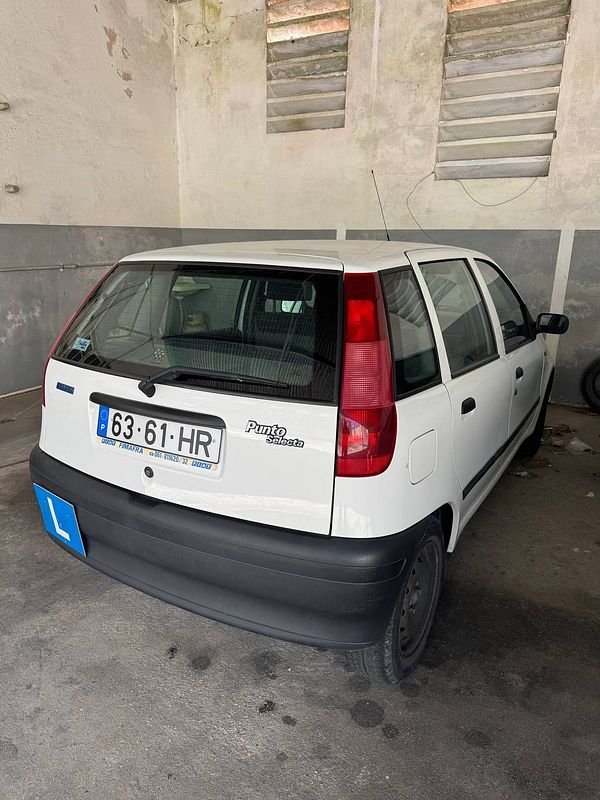 A white Fiat Punto parked in a garage with a learner's plate visible.