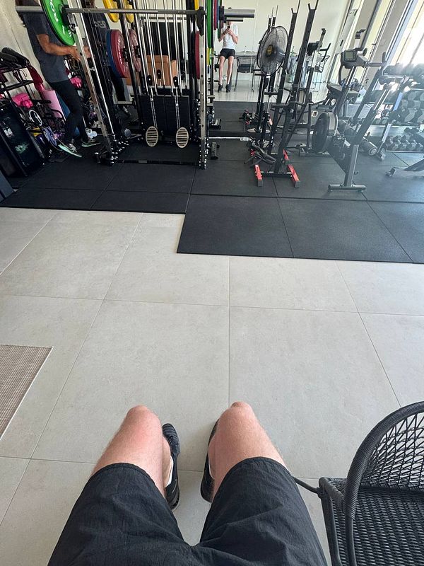 A view from a seated position in a home gym, showcasing various gym equipment and a workout area.
